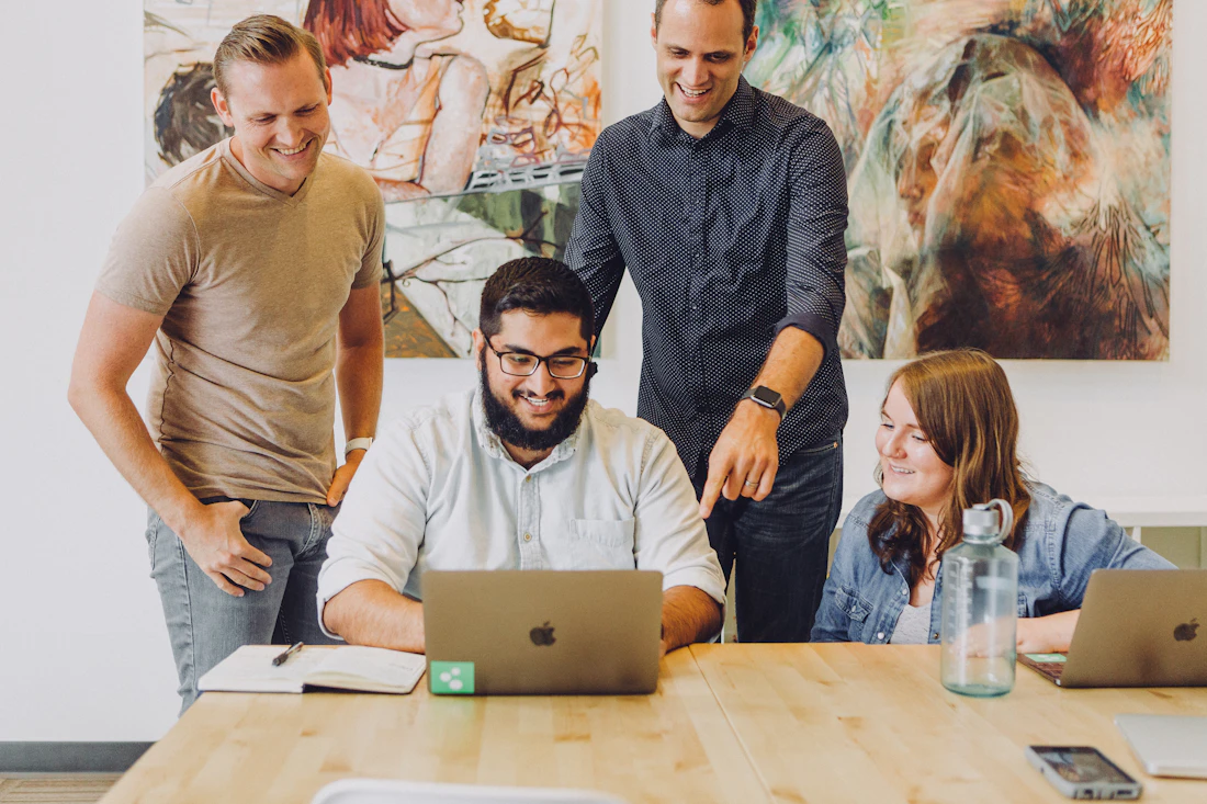 Coworkers smiling together while reviewing work on a laptop