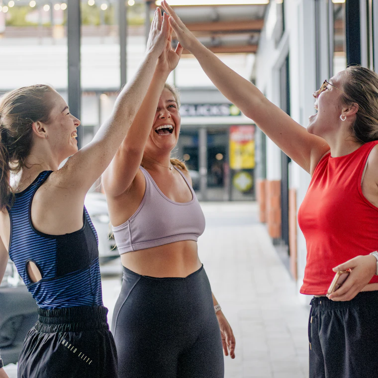 Three women giving each other a high five after a workout