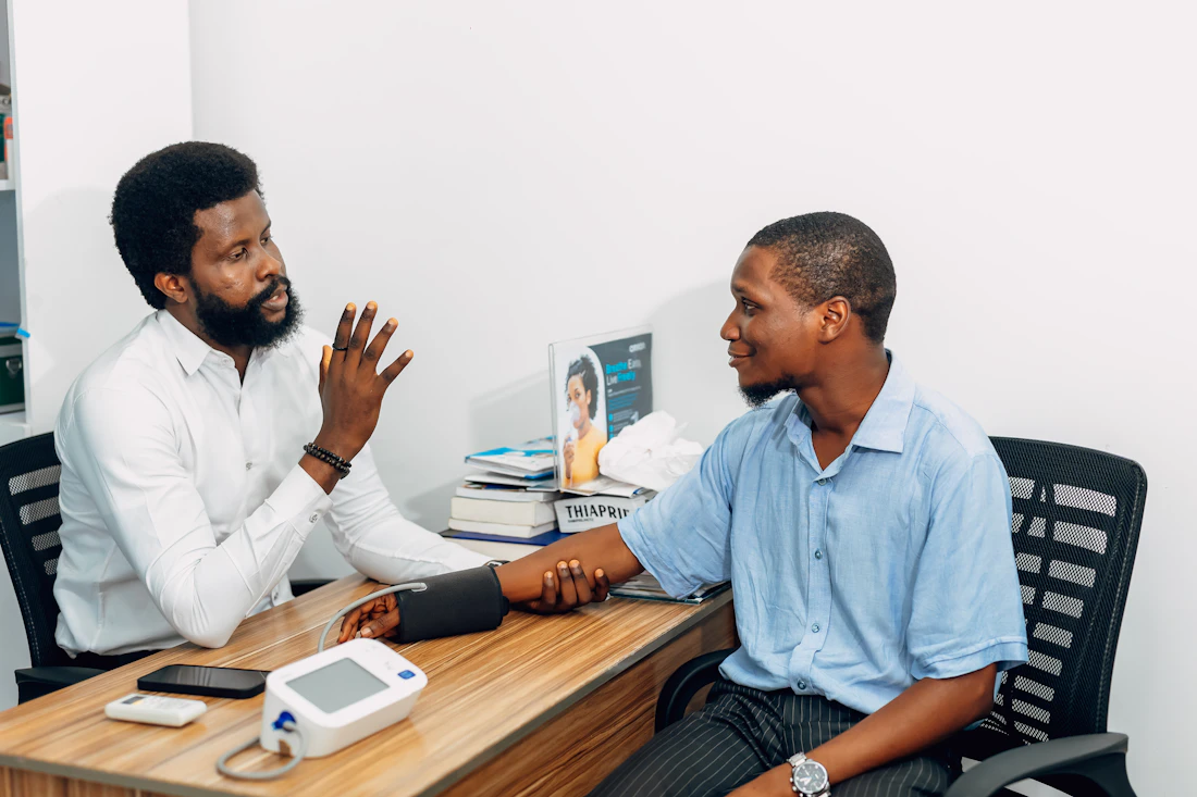 Health professional checking an employee's blood pressure at an office desk