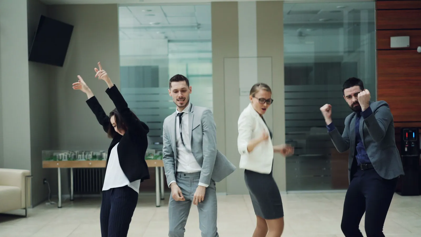 Energetic colleagues in business attire dancing together during a corporate fitness break