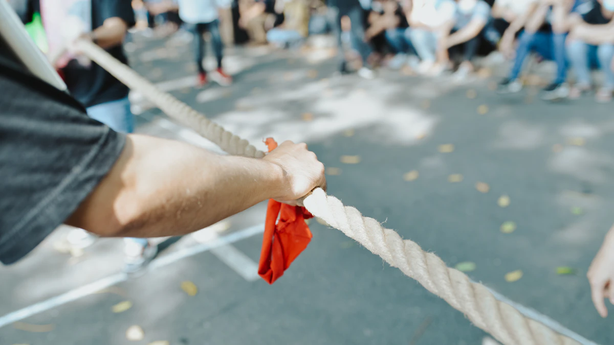 Close-up of hands gripping a rope during an outdoor tug-of-war team game