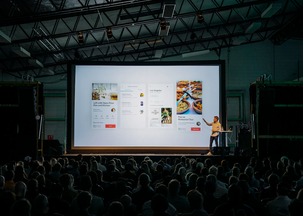 Speaker presenting to a large seated audience in an auditorium